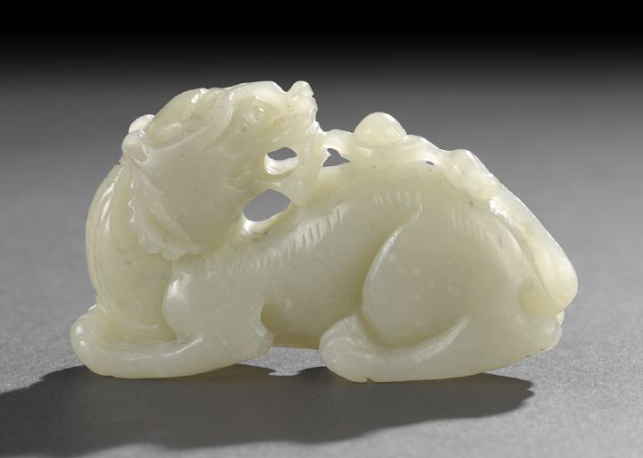 Chinese Carved Celadon Jade Figure of a Chimera,: Chinese Carved Celadon Jade Figure of a Chimera, late 18th century, the even celadon colored stone carved as a recumbent mythical animal with back-turned head emitting the Peal of Wisdom, the details