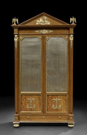 Empire-Style Ormolu-Mounted Satinwood Armoire,: Empire-Style Ormolu-Mounted Satinwood Armoire, the triangular pediment with an ormolu mount of a classical charioteer and flanked to either end by winged eagle finials, above a case fitted with two do