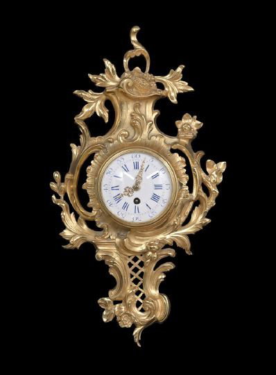Louis XV-Style Wall Clock: Louis XV-Style Wall Clock, the case formed of gilt-bronze rococo scrollwork, with lattice piercing in the base, the works fitted with a blue enameled dial, h. 22", w. 5", d. 3-1/2".