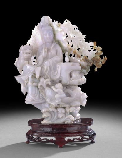 Large Chinese Carved Jade Buddhist Group: Large Chinese Carved Jade Buddhist Group, 20th century, the stone of pale-lavender with russet splashes, carved as the seated figure of the goddess Guanyin clad in a cowled robe holding a pearl in one