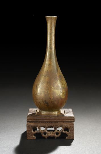 Elegant Japanese Bronze Ikibana Vase: Elegant Japanese Bronze Ikibana Vase, ca. 1910, of bottle form with elongated slightly flared neck, resting on a slightly splayed foot rim, the metal with mottled patination, presented on a later wood