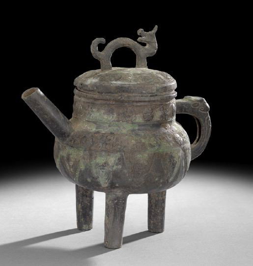 Chinese Bronze Zhou-Style Teapot: Chinese Bronze Zhou-Style Teapot, of rounded form, the lid with a Foo Dog finial, the handle in the form of a stylized animal, the body with elaboratge incised geometric patterns, raised on three tubu