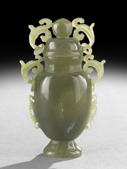 Chinese Carved Olive Jade Covered Vase: Chinese Carved Olive Jade Covered Vase, the even green stone carved as a baluster vase with floral flanges, foliate handles with loose rings and a fitted domed cover with foliate handles, loose rings 