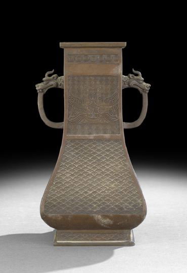 Chinese Cast Bronze Handled Vase: Chinese Cast Bronze Handled Vase in a Squared Baluster Shape, 19th century, the tapered body with horned dragon handles, the lower body with cast wave decoration, the upper body cast with archaic zoom