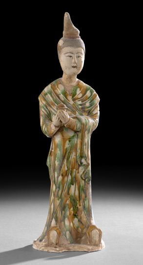Chinese Pottery Figure of a Female Attendant: Chinese Tri-Color and Painted Pottery Figure of a Female Attendant, Tang Dynasty (618-907) or later, the standing figure clad in tri-colored robes with upturned shoes and crowned with a high headdress
