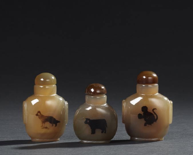 Three Chinese "Shadow" Agate Snuff Bottles: Three Chinese "Shadow" Agate Snuff Bottles, each carved in brown agate with black inclusions resembling animals, two bottles carved with mock mask ring handles, one plain, h. 2-1/4" to 2-5/8".