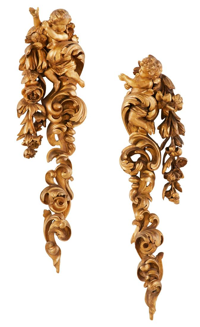 Pair of Italian Baroque-Style Giltwood Carvings: Pair of Large Italian Baroque-Style Giltwood Carvings 19th century, each depicting a cherub perched atop bold, carved and pierced scrollwork and leaves, with trailing lilies and roses on one side. h. 