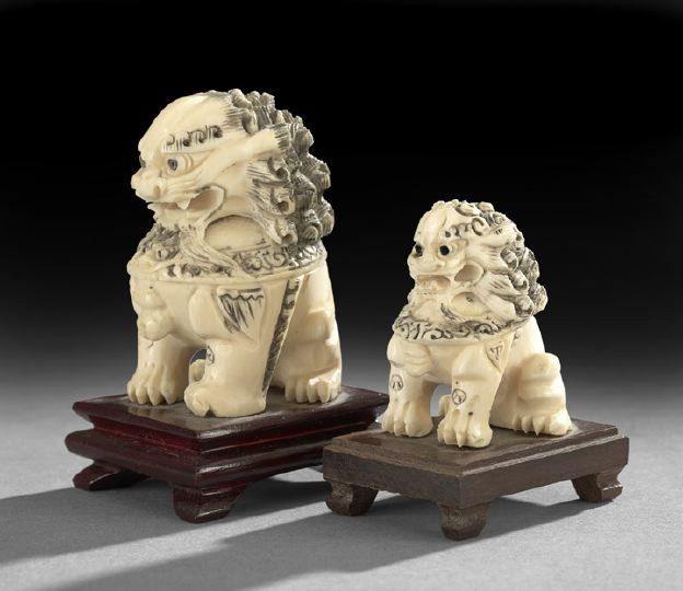 Two Chinese Carved Ivory Figures of Foo Dogs: Two Chinese Carved Ivory Figures of Imperial Foo Dogs, 20th century, each carved after bronze statues in the Imperial City, each seated on its haunches with inked details and attached to wooden bases,