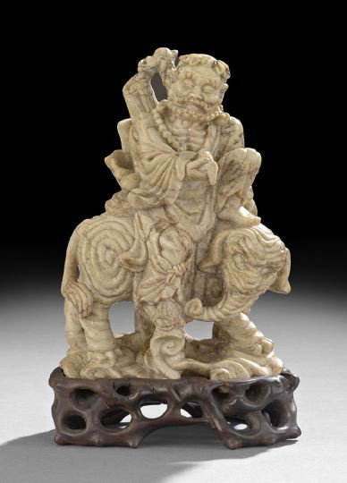 Good Chinese Carved Soapstone Group: Good Chinese Carved Soapstone Group, 19th century, the mottled beige colored stone carved as the figure of the Immortal Li Tieguai in the body of a homeless beggar, seated upon the back of an elephant