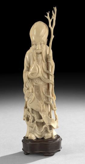 Chinese Ivory Figure of the God of Longevity: Chinese Carved Ivory Figure of the God of Longevity, carved in the round, the bald headed god clad in flowing robes with bats at his feet, holding his branched staff and the Peach of Immortality, h. 9