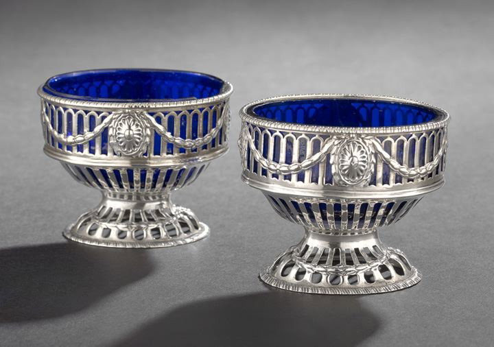 Pair of George III Sterling Silver Salt Cellars: Pair of George III Sterling Silver Salt Cellars, hallmarked London, 1774-1775, by Robert Hennell I, each of oval form with sloped bottom and raised on a conforming domed foot, decorated throughout wit