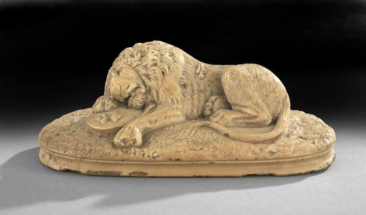 Plaster of a Lion in the Renaissance Taste: Plaster of a Wounded Lion in the Renaissance Taste, depicted sleeping on a French shield with an enameled tan finish, h. 25", w. 6", d. 3".