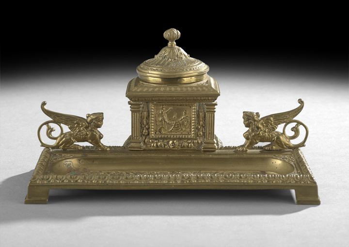 Intricate Cast Brass Inkwell/Pen Holder: Intricate Cast Brass Inkwell/Pen Holder in the Classical-Style, early 20th century, the front portion with a recessed tray and featuring winged sphinxes at the back edge along with a reservoir for ink