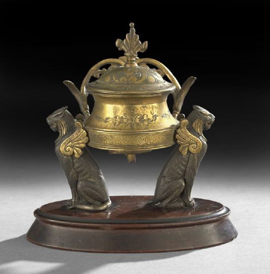 Napoleon III Egyptian-Revival Encrier: Napoleon III Egyptian-Revival Encrier, fourth quarter 19th century, the oval rouge marble base supporting a pair of patinated-bronze and gilt-winged lions supporting a gilt inkpot with a scrolled pen 