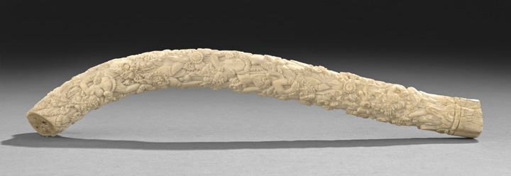 Unusual Indian Carved Bone Specimen: Unusual Indian Carved Bone Specimen, the piece retaining the shape of the original bone with one arc exhibiting the bone's internal structure, well-carved all over with myriad figures, flowers and fol