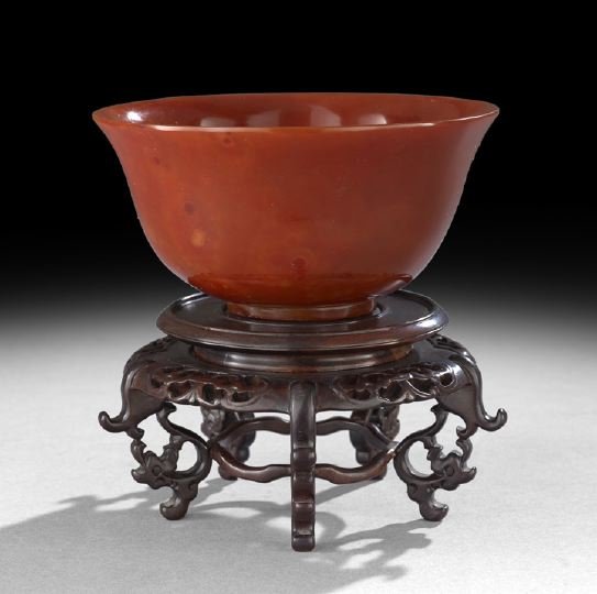 Good Chinese Carved Carnelian Bowl: Good Chinese Carved Carnelian Bowl, of inverted bell shape with circular foot rim and flared lip rim, the stone of even red color, elaborate wooden display stand, dia. 6-1/4".