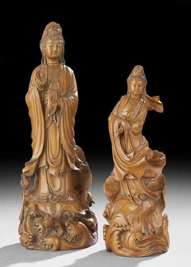 Group of Two Chinese Boxwood Figures of Guanyin: Group of Two Chinese Boxwood Figures of Guanyin, 20th century, one figure dressed in loose robes with a vessel in one hand, the other in a mudra position, raised above waves on a lotus leaf, h. 19-3/4