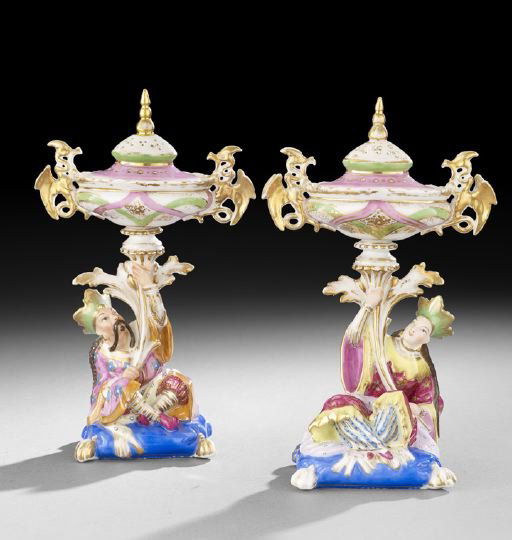 Pair of Paris Porcelain Potpourri Holders: Pair of Paris Porcelain Potpourri Holders, second quarter 19th century, in the style of Jacob Petit, each featuring a seated oriental figure holding the oval covered potpourri containers aloft, and re