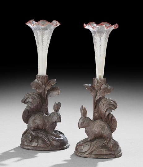 Pair of Black Forest Carved Vases in Stands: Pair of Black Forest Carved Vases in Stands, fourth quarter 19th century, each base depicting a rabbit on a stump, wheel-cut glass posey holders trimmed in red, and "growing" from the top of each stan