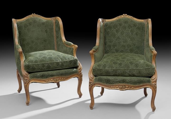 Pair of Louis XV-Style Fruitwood Bergeres: Pair of Louis XV-Style Fruitwood Bergeres, each with a domed and padded back surmounted by a floral crest, joined by shaped sides and padded arms to the cushioned seat, raised on molded cabriole legs 