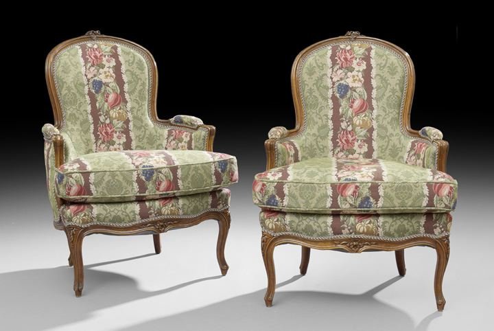 Pair of Louis XV-Style Fruitwood Bergeres: Pair of Louis XV-Style Fruitwood Bergeres, each with a domed and padded back surmounted by a floral crest, joined by low padded arms to the cushioned seat, raised on molded cabriole legs headed by flo