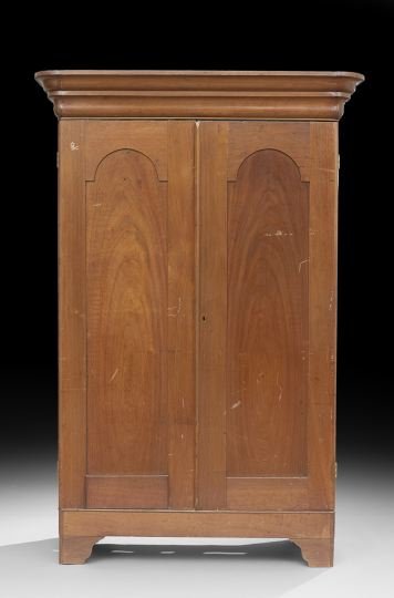 American Vernacular Walnut Double Door Armoire: American Vernacular Walnut Double Door Armoire, second quarter 19th century, the top with a double ogee-molded cornice above a pair of doors, each with a tombstone-shaped panel and raised on a base wi