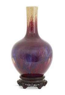 Chinese Flambe-Glazed Porcelain Bottle Vase: Chinese Flambe-Glazed Porcelain Bottle Vase Qing Dynasty (1644-1912), the neck streaked with a tan glaze and the body with a blue/lavender glaze, over a plum ground, on a carved and pierced hardwood b