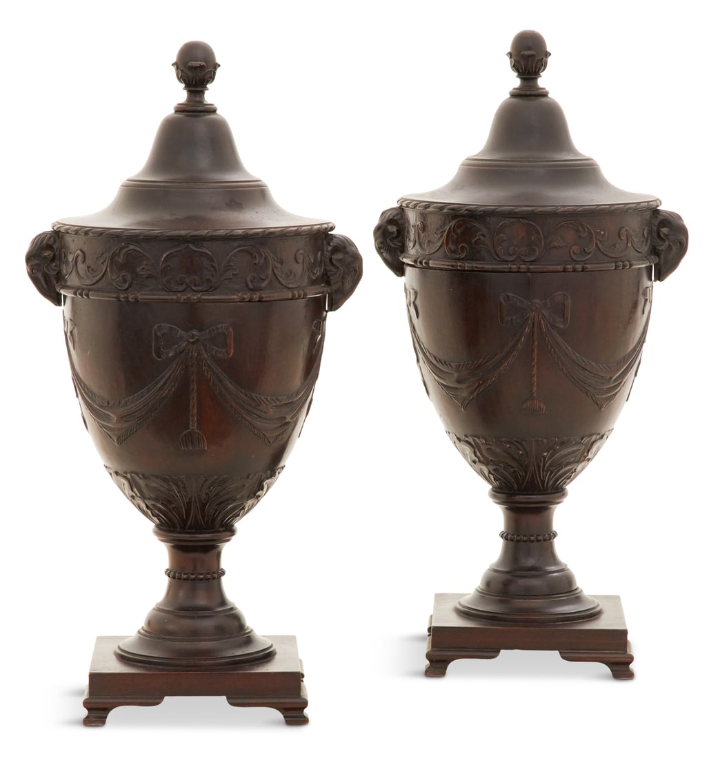 Pair of Mahogany Knife Urns in the Adam Taste: Pair of Mahogany Knife Urns in the Adam Taste first quarter 20th century, the ogee covers suspended on ratcheted support rods, opening to reveal fitted interiors, mounted with carved ram's-head handle