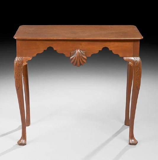 Queen Anne-Style Mahogany Tea Table: Queen Anne-Style Mahogany Tea Table, 19th century, the rounded rectangular top above an arched frieze centered by an applied shell to either side, raised on cabriole legs headed by acanthine carving a