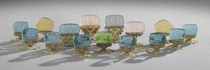 Fifteen Austrian Gilt Metal and Intaglio Glass Pla: Fifteen Austrian Gilt Metal and Intaglio Glass Placecard Holders, first quarter 20th century, probably Julius Spitzer & Co., Vienna, each with an engraved or filigree stand, some with rhinestone decor