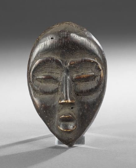 Carved and Stained African Passport in the form of: Carved and Stained African Passport in the form of an Diminutive Mask, 18th century, the backside bearing a museum inventory number EHX 1031, h. 4", w. 2-3/4".