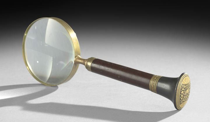Continental and Mahogany Magnifying Glass: Continental Ebony, Gilt-Bronze and Mahogany Magnifying Glass, ca. 1900, the oval end cap decorated with gilt-bronze vines on an ebony field with engraved end panels, the handle sides mahogany with inl