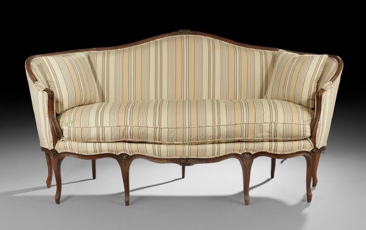 Provincial Fruitwood Settee: Provincial Fruitwood Settee, late 19th century, the domed and padded back surmounted by a floral crest and joined by rounded and downswept padded arms to the cushioned seat, raised on molded cabriole 