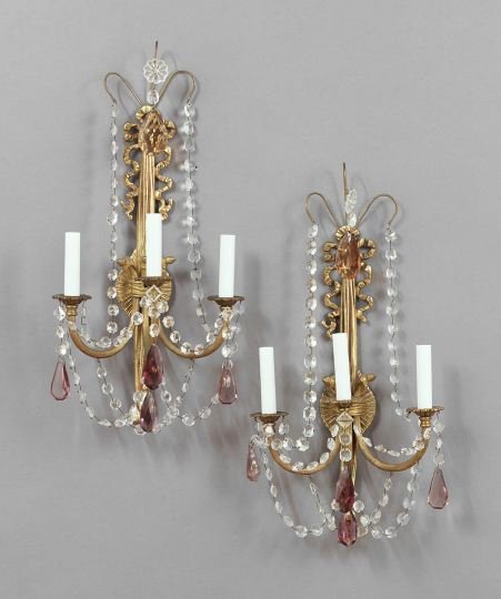 Pair of Continental Polished Bronze Wall Sconces: Pair of Continental Polished Bronze Three-Light Wall Sconces, in the neoclassical style, the ribbed arms supported on bowknot and tassel-back plates and hung with festoons of clear and mauve prisms, h