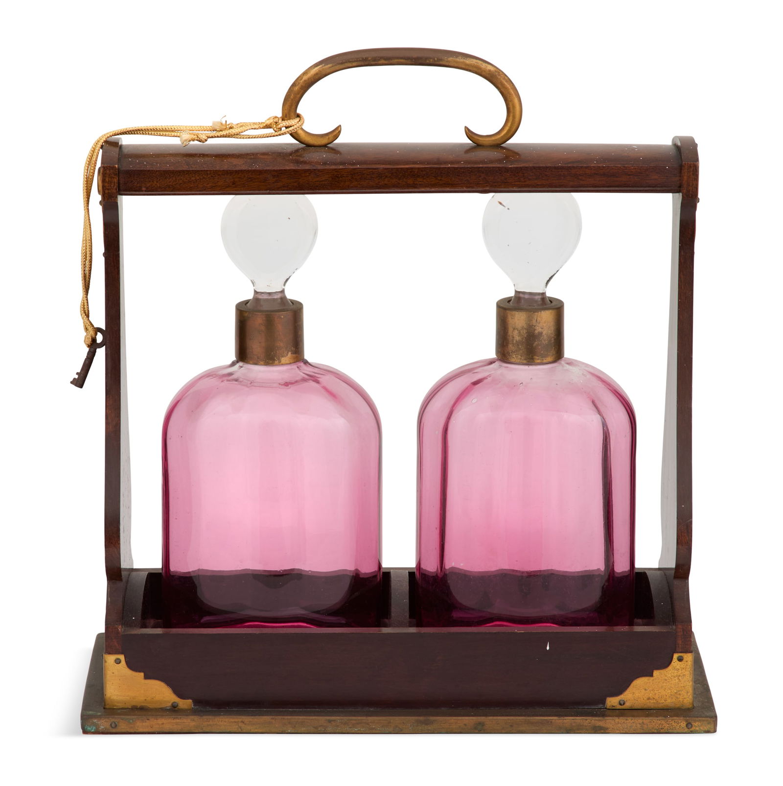 English Hardwood, Glass and Brass Tantalus: English Hardwood, Glass and Brass Tantaluslate 19th century, the brass-bound tropical hardwood tantalus set with a pair of blown-glass cranberry decanters with cut-glass bases and colorless glass stop
