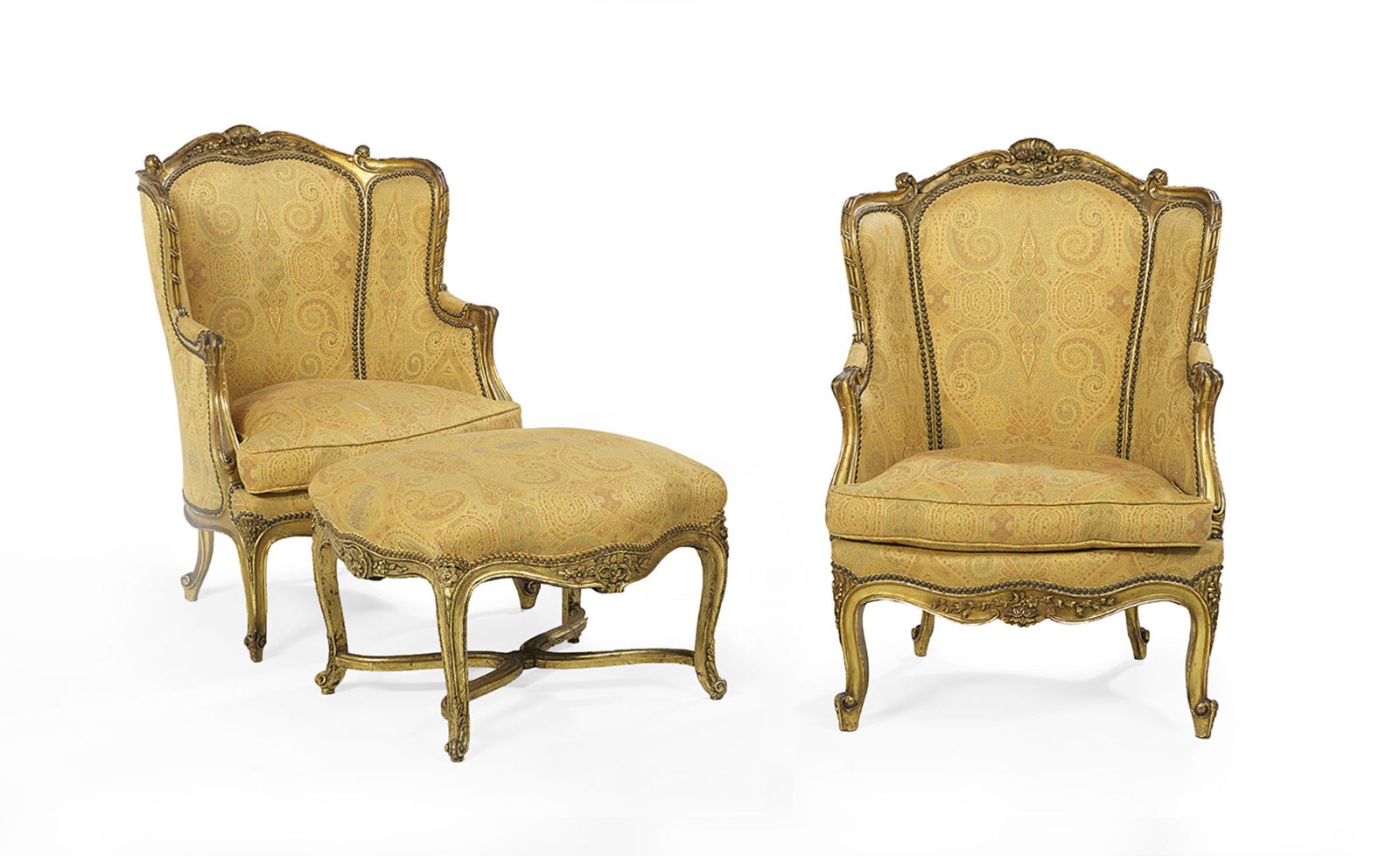 Pair of Bergeres avec Oreilles and a Stool: Pair of Giltwood Bergeres avec Oreilles and a Stoolearly 20th century, each chair with a padded domed back surmounted by a shell and floral crest, joined by shaped and padded sides and arms to the cus