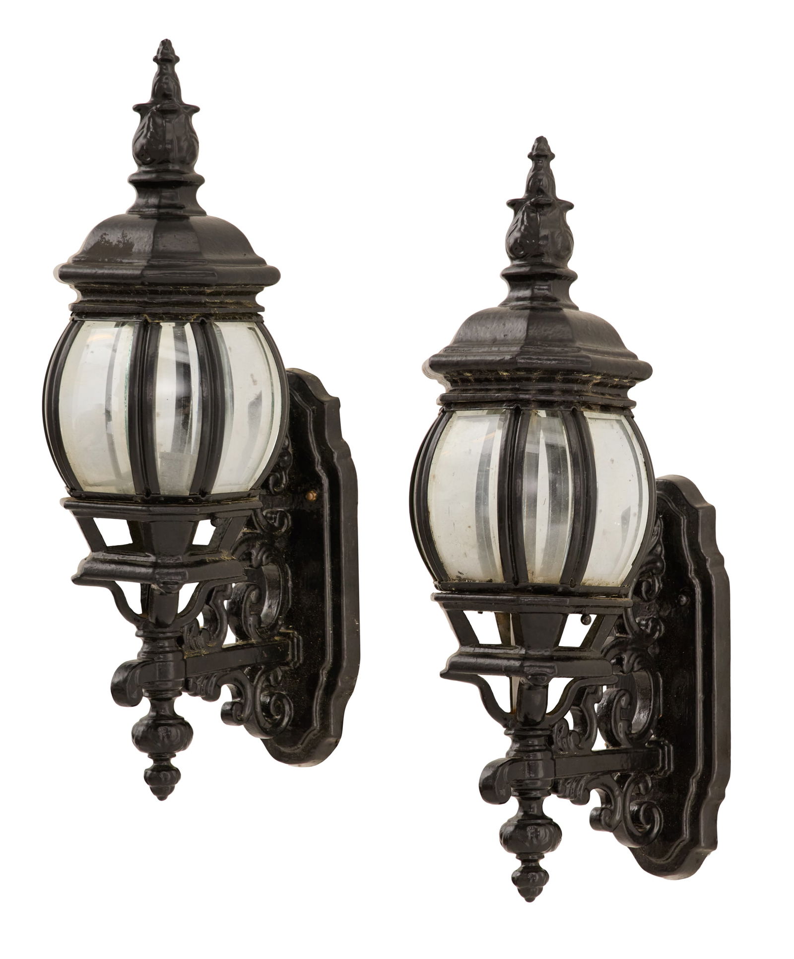 Pair of Black Metal and Glass Exterior Lights: Pair of Black Metal and Glass Exterior Lightsthe faceted lantern-form lights set with steeple-form finials, the sides set with beveled glass, supported on arms decorated with scrolled decoration to mo