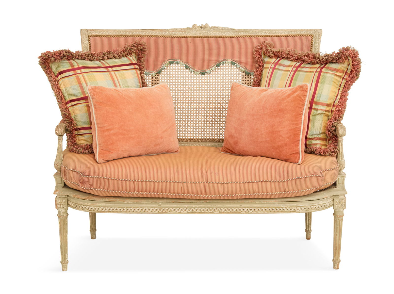 Louis XVI-Style Polychrome and Caned Settee: Louis XVI-Style Polychrome and Caned Setteeca. 1900, the back with a floral-carved crest over a caned panel, the caned seat with a reversible loose cushion and four pillows, raised on fluted legs.h. 3