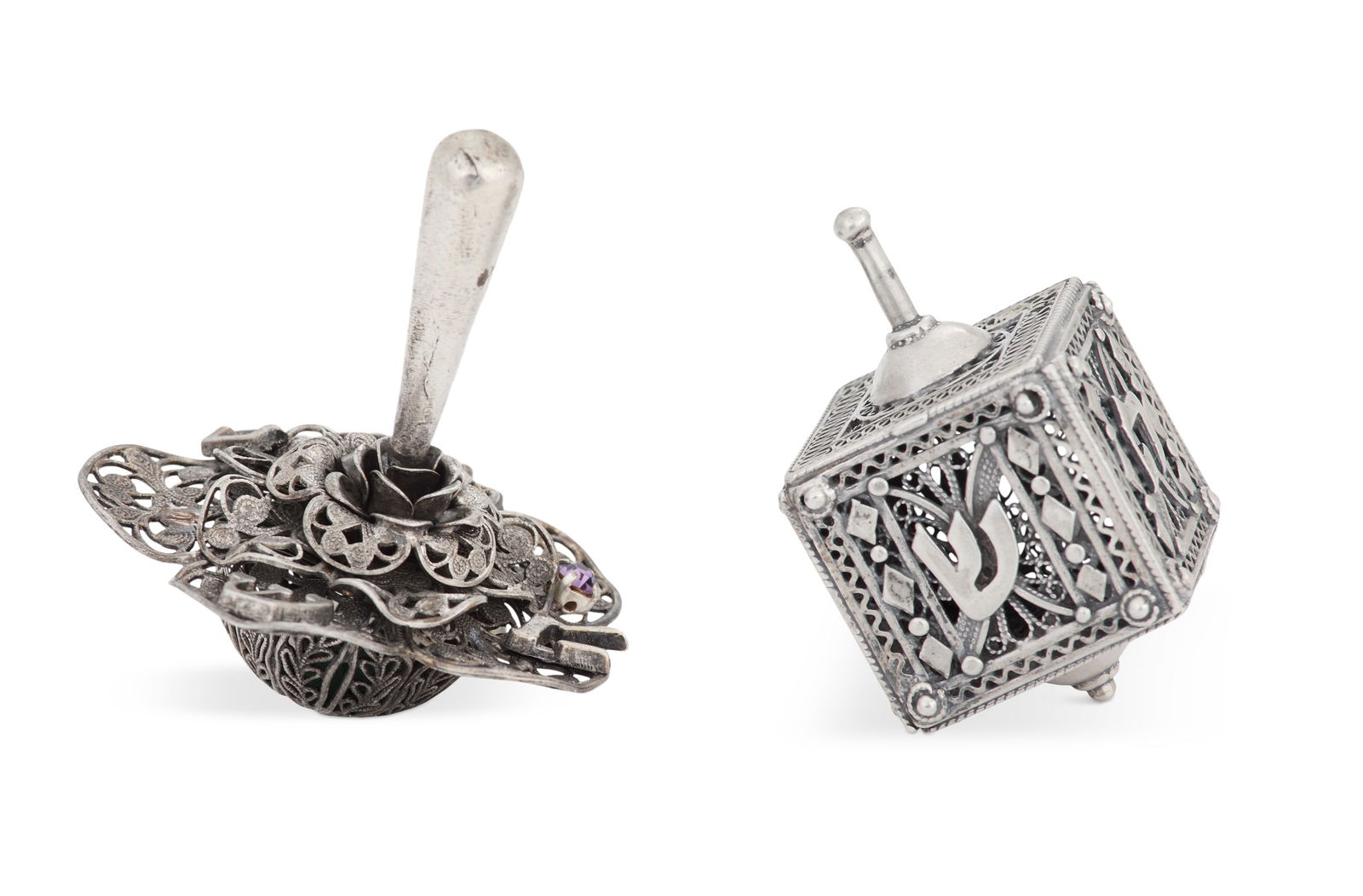 Two Sterling Silver Filigree Dreidels: Two Sterling Silver Filigree Dreidels contemporary, one of traditional form, Shoham Judaica, Jerusalem, h. 2", w. 1-1/8"; and one of floral disc form with purple "jewel", h. 2-1/2", dia. 2-1/4". 2.04