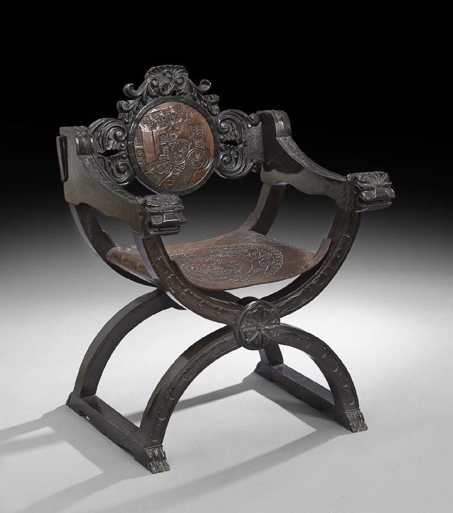Spanish Colonial Leather Savonarola Chair: Spanish Colonial Ebonized and Embossed Leather Savonarola Chair, early 20th century, the carved back centered by a circular leather panel depicting a carriage, the leather sling seat with an embossed