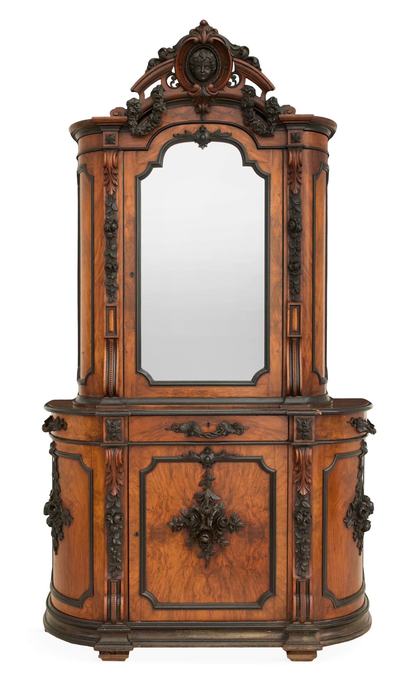 Napoleon III Walnut and Parcel-Ebonized Cabinet: Napoleon III Figured Walnut and Parcel-Ebonized Cabinet 19th century, in two parts, the upper case with a pierced crest centered by a carved child's bust and flanked by floral swags, above a single mi