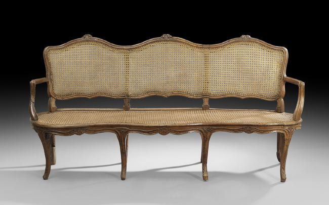 Provincial Louis XV Walnut Settee: Provincial Louis XV Walnut Settee, late 18th century, the triple-domed caned back surmounted by floral crests and joined to the shaped caned seat by molded arms, raised on molded legs ending in foliat