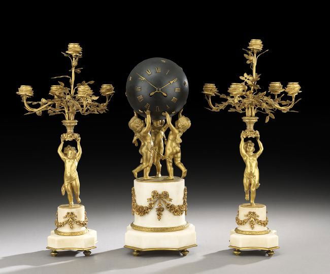 French Gilt-Bronze and Marble Clock Garniture: French Gilt-Bronze and Marble Clock Garniture, fourth quarter 19th century, depicting three cupids bouncing a star-studded "ball" mounted with a clock, the bronze-mounted marble base supports the figu