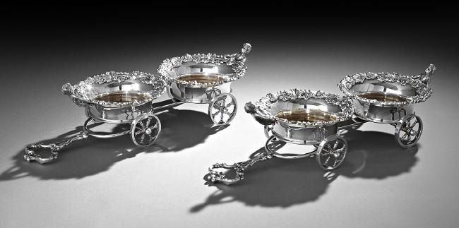 Pair of English Silverplate Wine Trolleys: Pair of English Silverplate Wine Trolleys, second half 20th century, in the rococo taste, each with a pair of coasters with applied rococo scroll rim and turned wooden base, crested by demi-putti, fit