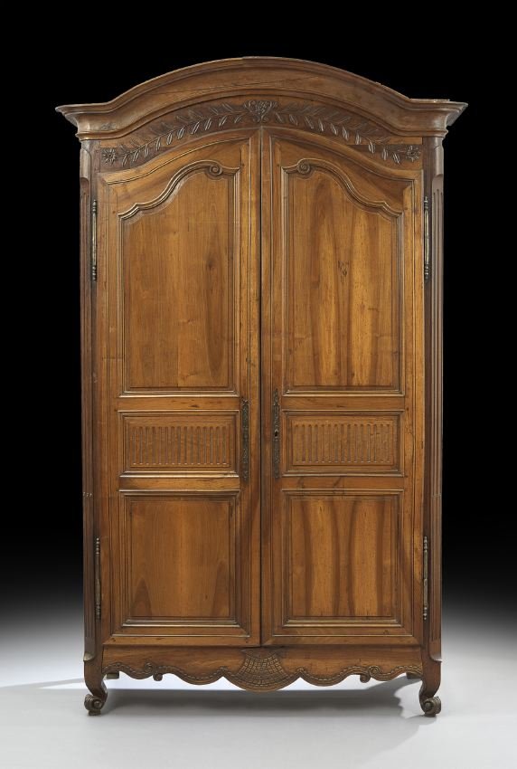 French Provincial Fruitwood Armoire: French Provincial Fruitwood Armoire, early 19th century, the domed and molded cornice above a case fitted with a foliate-carved frieze over two long doors, each inset with three panels, the central on