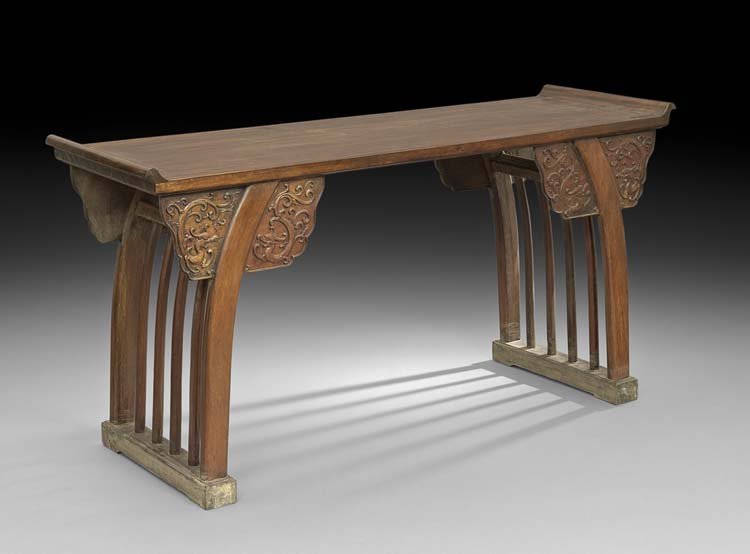 Chinese Mahogany Altar Table: Chinese Mahogany Altar Table, the rectangular top with raised ends above shaped legs headed by dragon and scroll carving, joined by spindled ends and ending in block feet, h. 31", w. 63-1/2", d. 21".