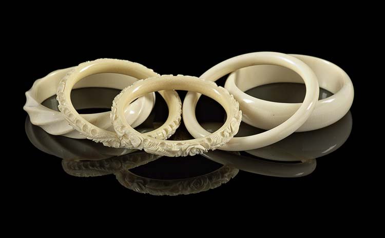 Five Carved Ivory Bangle Bracelets: Five Carved Ivory Bangle Bracelets, one carved with roses and leaves, one carved with dragons, one carved as a semi-circle, one carved as a fluted rope design and the last example in a circle design,