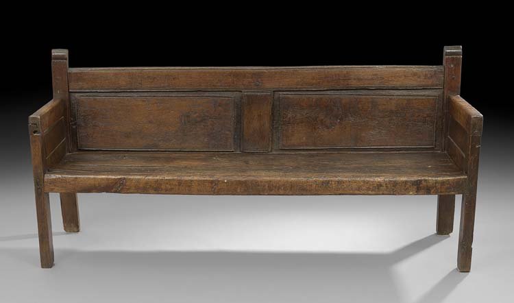 Provincial Oak Settee: Provincial Oak Settee, 17th century, the low paneled back surmounted by shaped finials and joined to the planked seat by closed paneled arms, raised on plank legs, h. 33-1/2", w. 70-1/2", d. 21-1/2". 