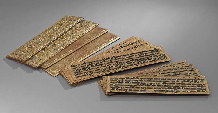 Two Burmese Gilt Buddhist Prayer Books: Two Burmese Gilt and "Jeweled" Buddhist Prayer Books with Palm Leaf Pages, the wooden covers decorated with gilt on a red ground, with raised scrollwork and "jewels" on the front, the interior text in