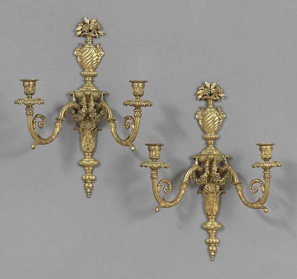 Pair of Napoleon III Gilt-Bronze Sconces: Pair of Napoleon III Gilt-Bronze Two-Light Sconces, in the Louis XVI style, with leaf-molded backplates and urn finials, the scroll-molded candle arms set with leaf-molded drip pans and matching candl
